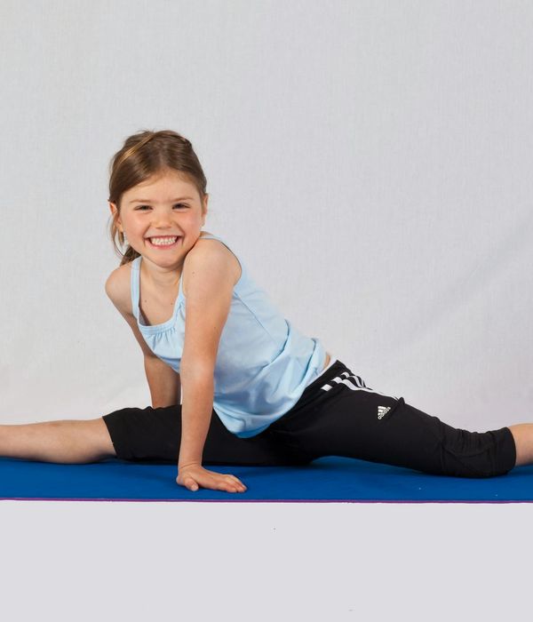 Happy child in a playful yoga pose on a colorful mat.