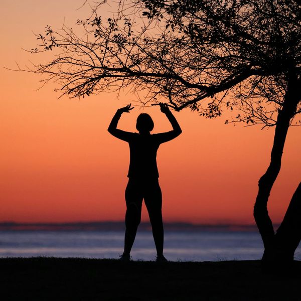 Silhouette of a child balancing in a yoga tree pose.